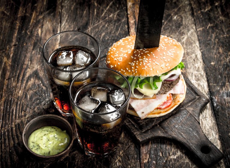 Street food. Big burger with cola and sauce. On a wooden background.